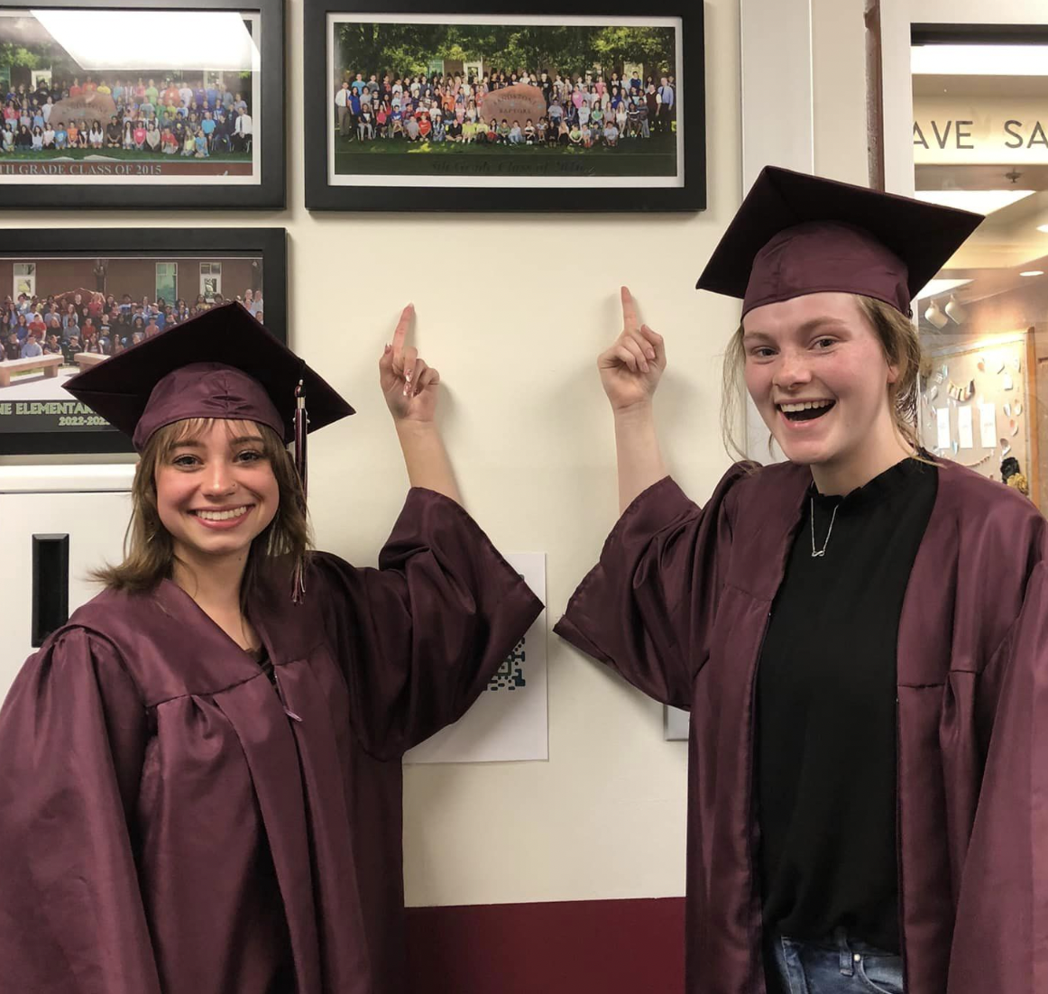 Graduation high school students pointing to a past picture of themselves on the wall. 